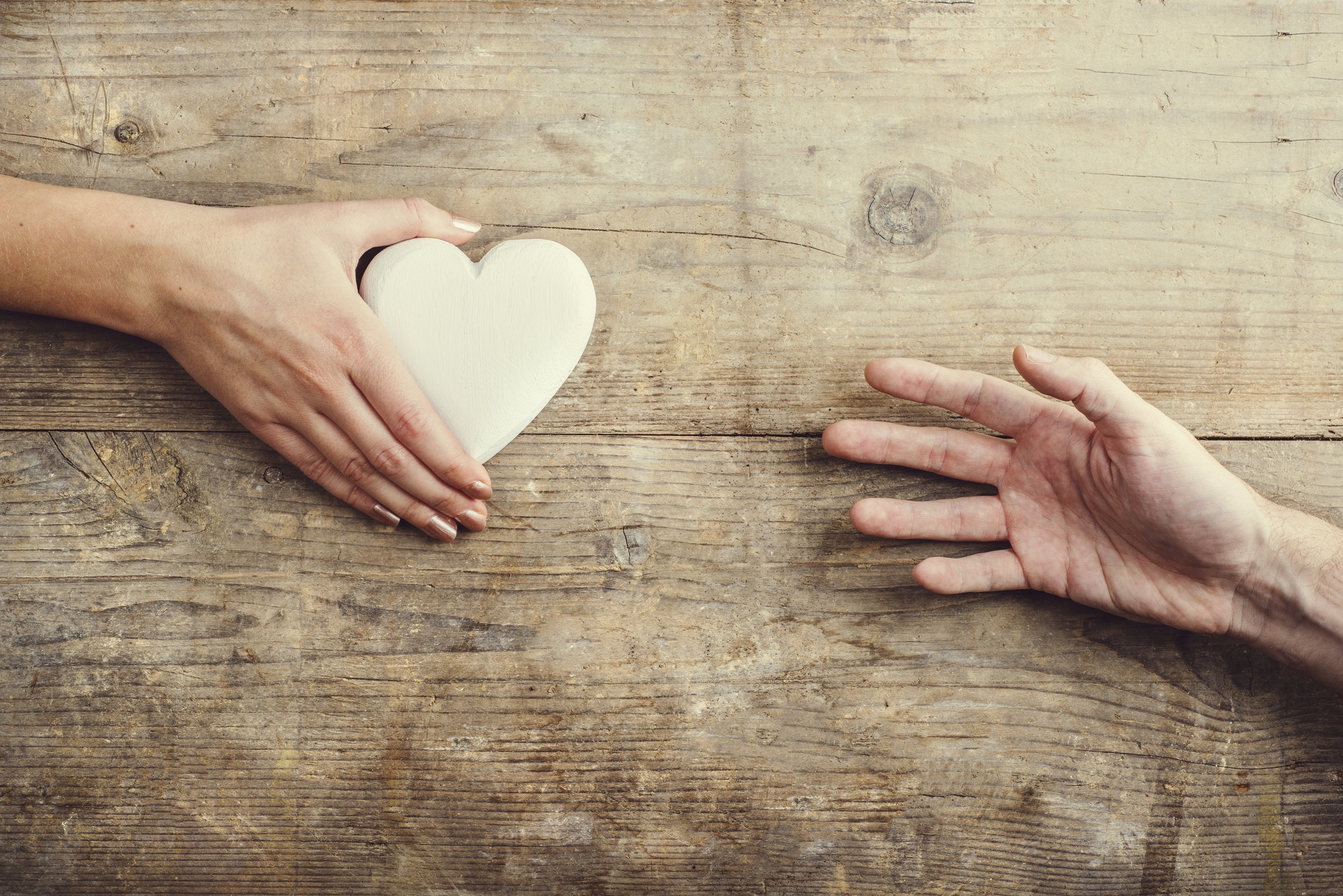 Man reaching for a heart to woman.